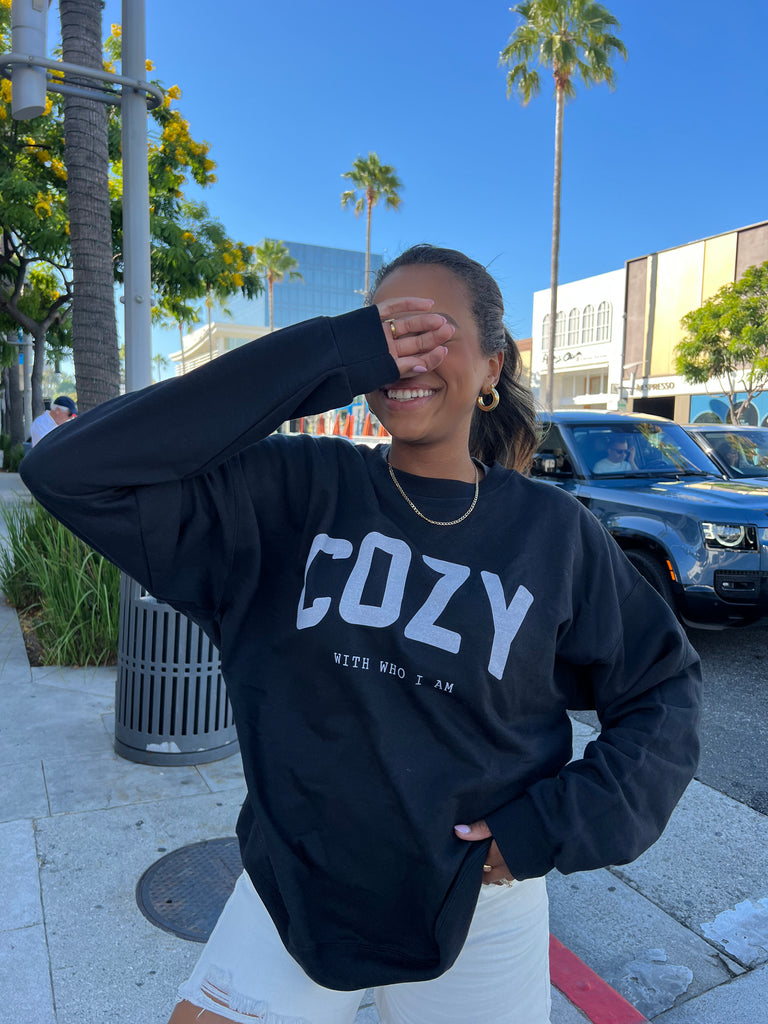 Black crewneck with "COZY" in block letters followed by "with who I am" in smaller typewriter font