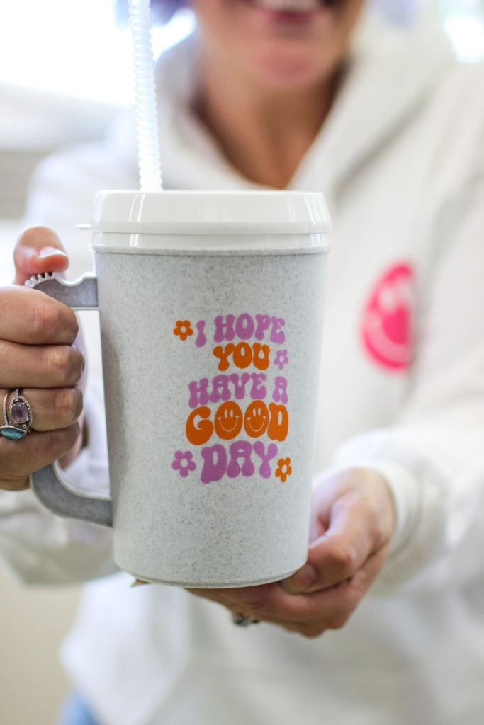 22 oz mega mug with lid and straw with the phrase "I hope you have a good day" in purple and orange