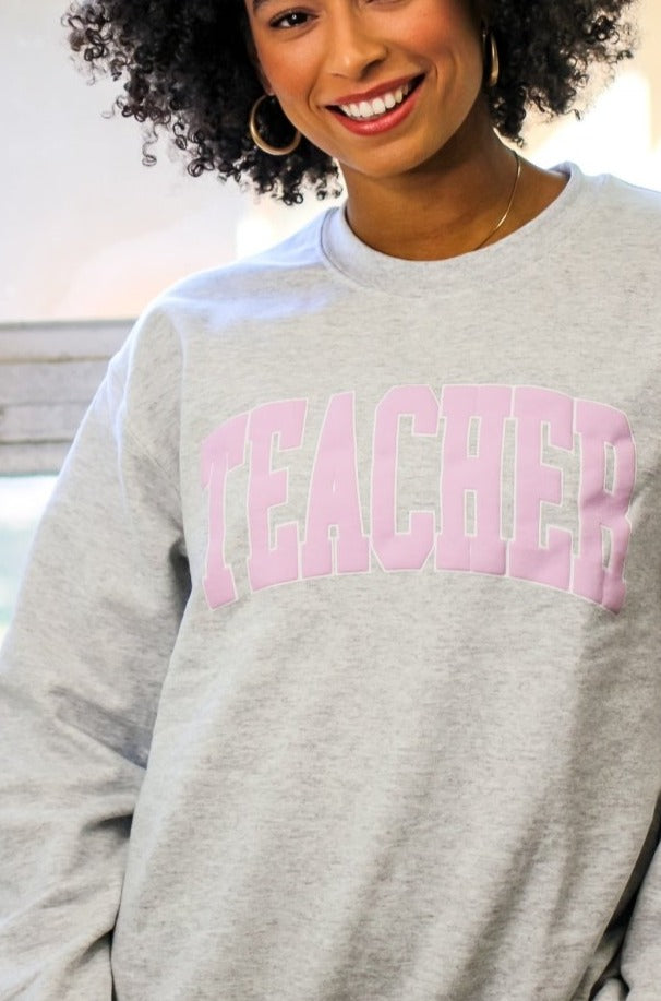Gray crewneck sweatshirt with TEACHER in light pink block letters 